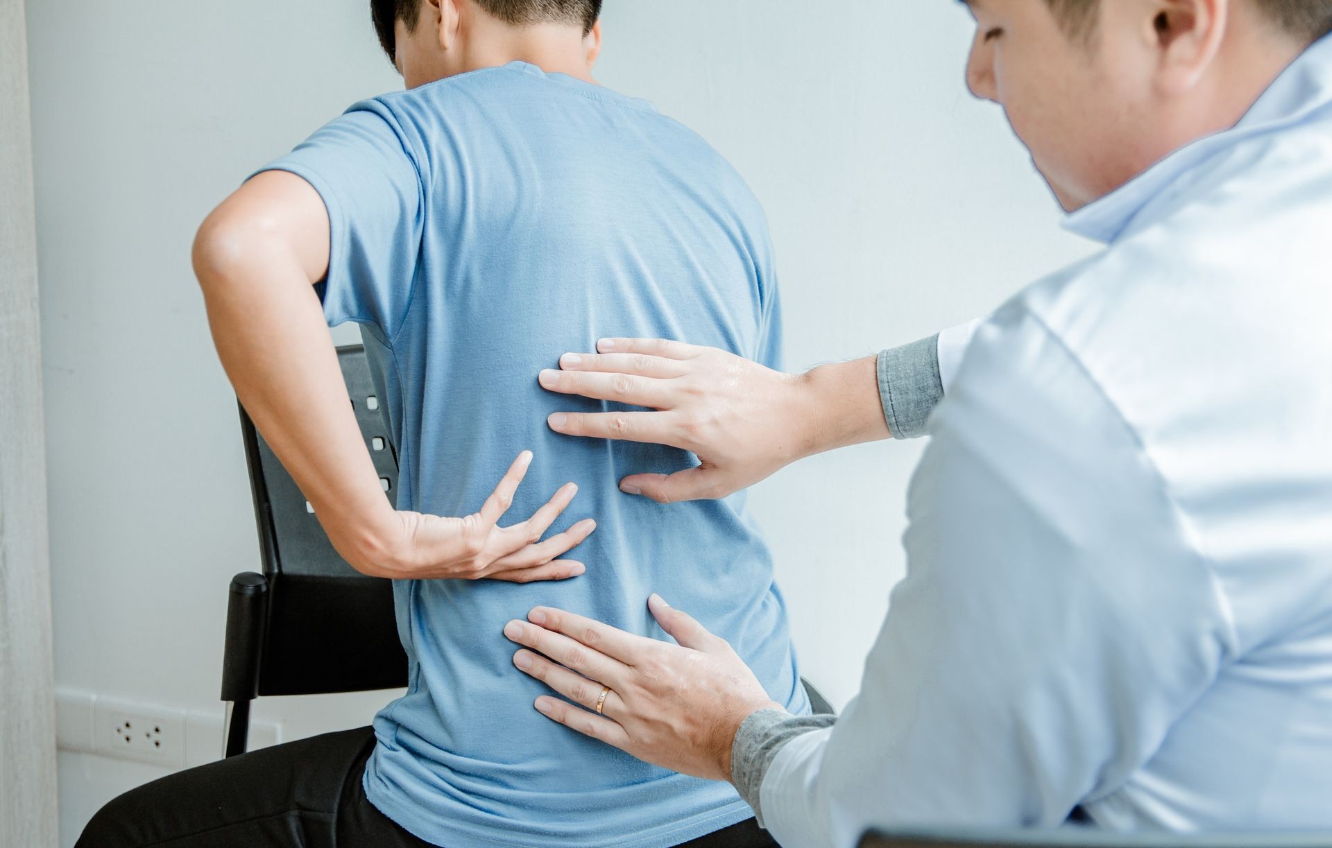 Male Patient in blue shirt visiting Doctor's Office With Backache